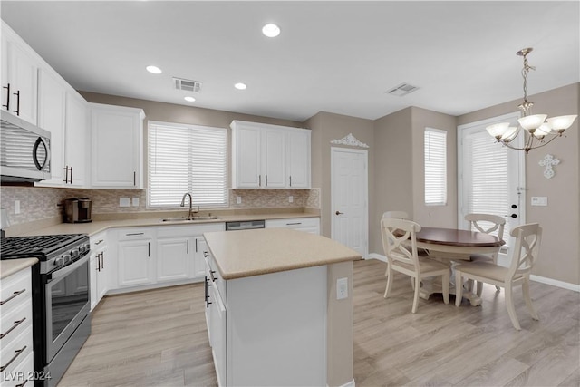 kitchen featuring stainless steel appliances, sink, pendant lighting, light hardwood / wood-style flooring, and a kitchen island