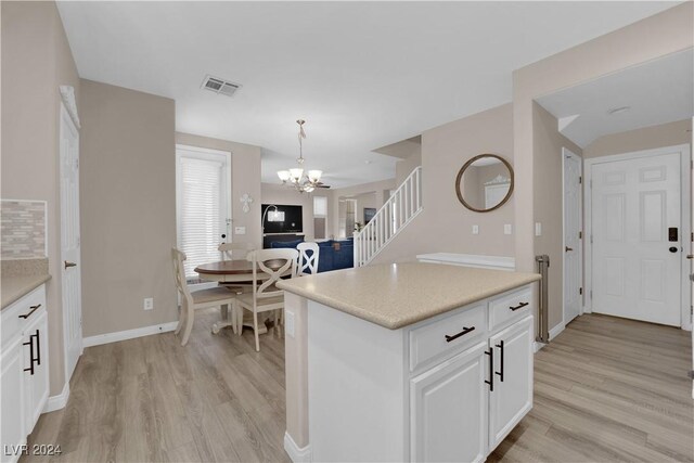 kitchen with white cabinetry, pendant lighting, and light hardwood / wood-style floors