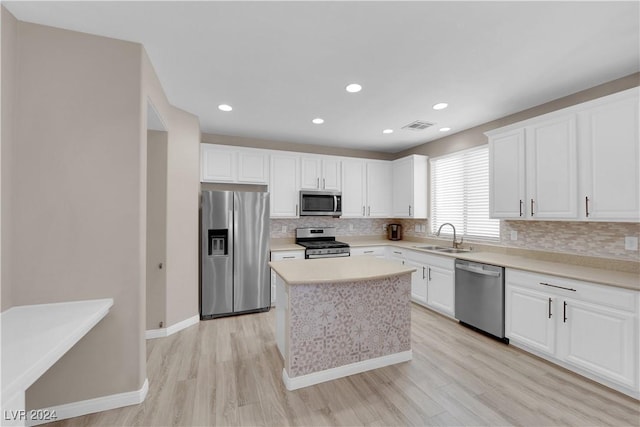 kitchen with a center island, white cabinets, sink, light hardwood / wood-style flooring, and appliances with stainless steel finishes