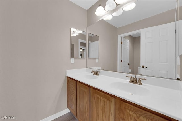 bathroom with vanity, wood-type flooring, a notable chandelier, and toilet