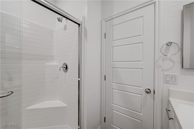 bathroom featuring a shower with door and vanity