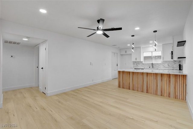 kitchen with white cabinetry, pendant lighting, light hardwood / wood-style floors, and kitchen peninsula