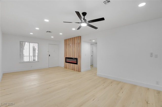 unfurnished living room featuring a fireplace, heating unit, ceiling fan, and light hardwood / wood-style flooring