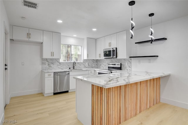 kitchen with white cabinetry, kitchen peninsula, stainless steel appliances, and light hardwood / wood-style floors