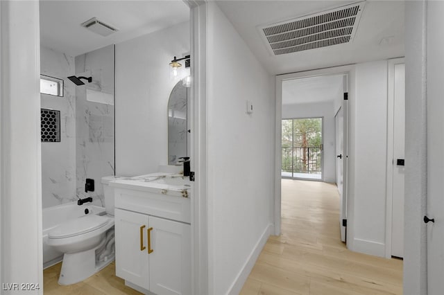 full bathroom featuring wood-type flooring, vanity, toilet, and tiled shower / bath combo