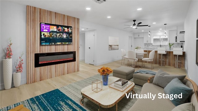 living room with light wood-type flooring and ceiling fan