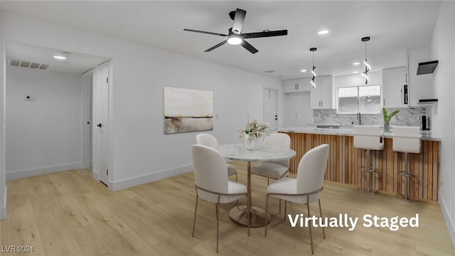 dining area featuring ceiling fan, sink, and light hardwood / wood-style flooring