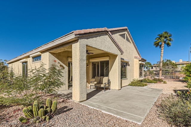 back of property with ceiling fan and a patio area