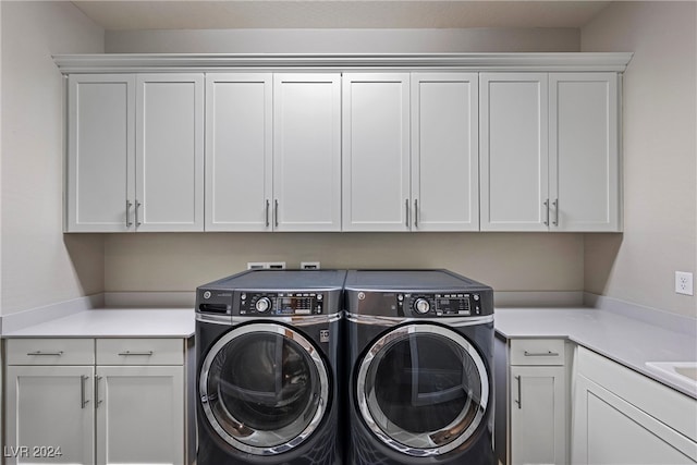 clothes washing area with washing machine and dryer and cabinets