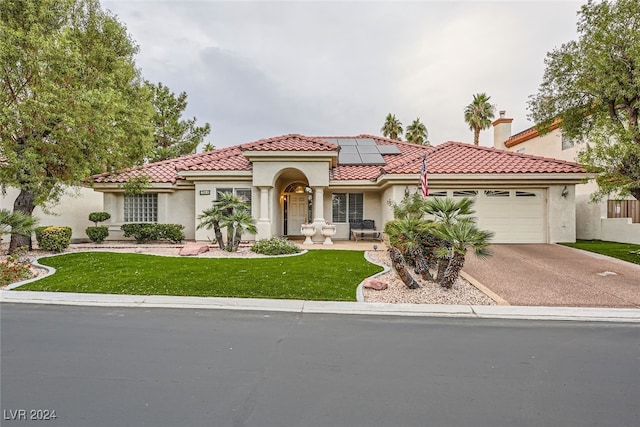 mediterranean / spanish-style home with a front lawn, a garage, and solar panels