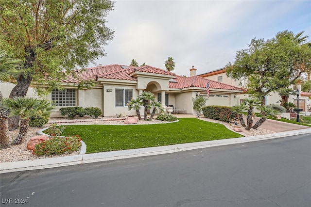 mediterranean / spanish home with a garage and a front lawn