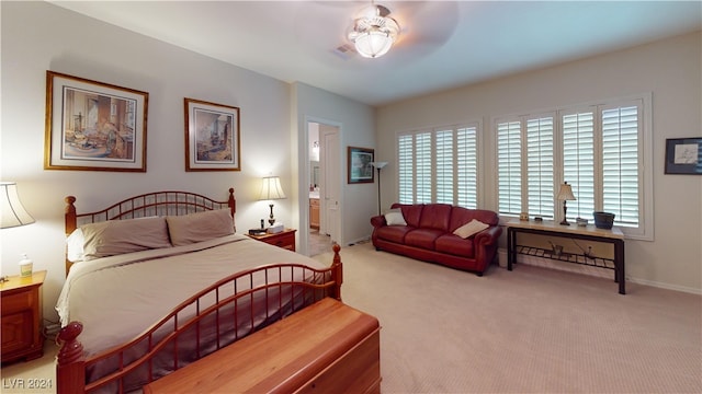 bedroom with ensuite bath, light carpet, and ceiling fan