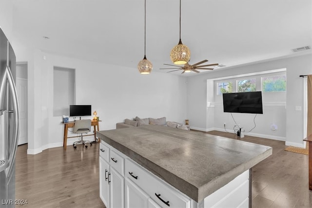 kitchen with decorative light fixtures, white cabinets, dark wood-type flooring, ceiling fan, and a center island