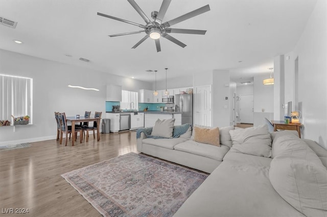 living room with ceiling fan, sink, and light hardwood / wood-style floors