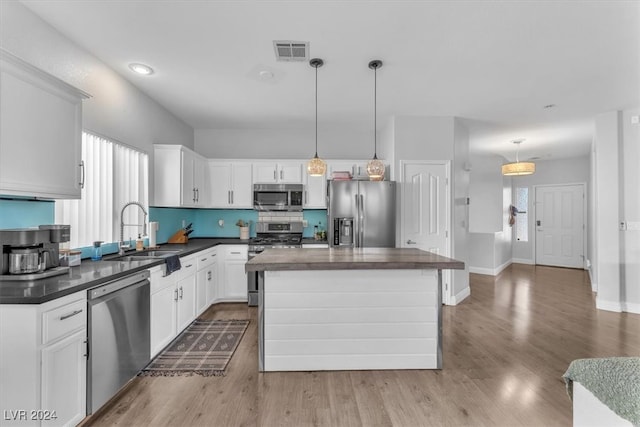 kitchen with stainless steel appliances, sink, pendant lighting, and a center island