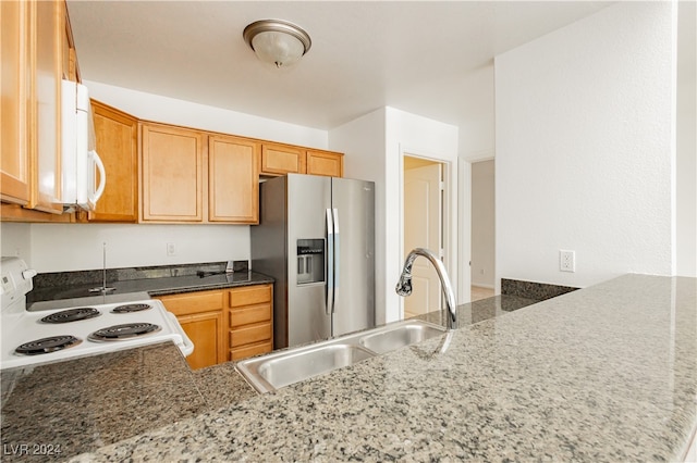 kitchen with white appliances, stone counters, sink, and kitchen peninsula