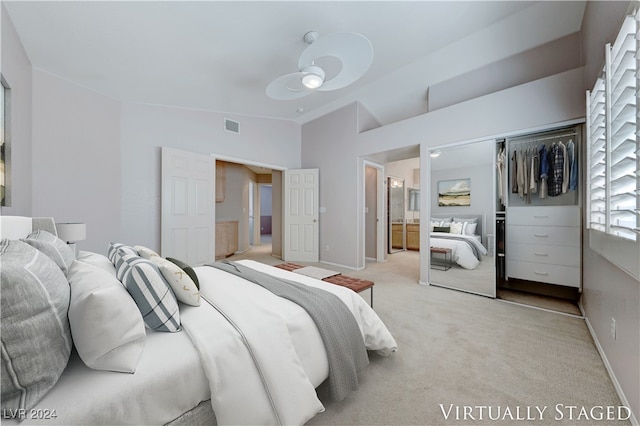 carpeted bedroom featuring a closet, ceiling fan, and ensuite bath