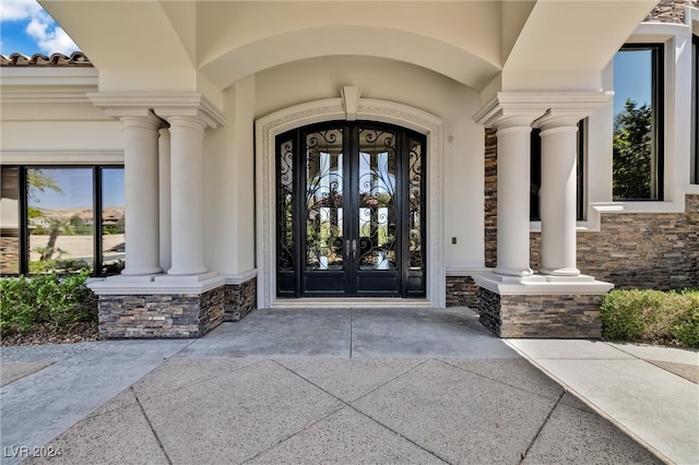 view of exterior entry with a porch and french doors