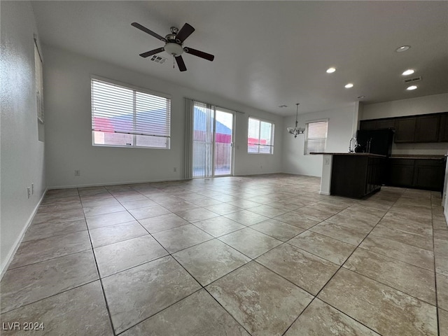 unfurnished living room featuring ceiling fan with notable chandelier and light tile patterned floors