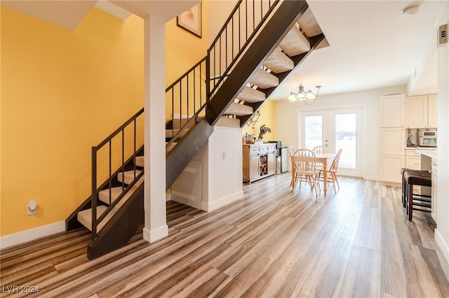 stairs featuring hardwood / wood-style flooring, french doors, and a chandelier