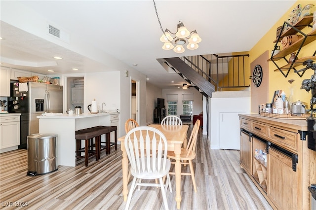 dining area with ceiling fan with notable chandelier, sink, and light wood-type flooring