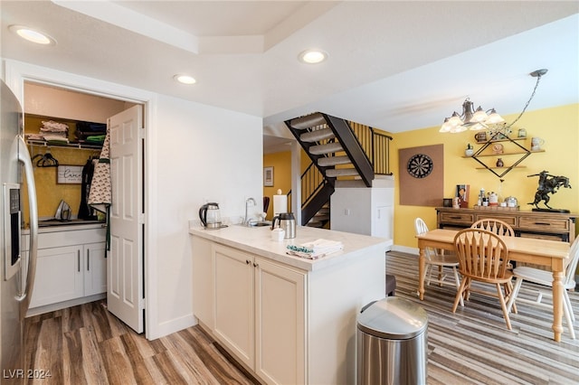 kitchen with white cabinetry, hanging light fixtures, stainless steel fridge with ice dispenser, and hardwood / wood-style floors