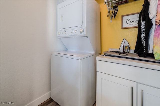 laundry area featuring stacked washer / drying machine and dark hardwood / wood-style floors