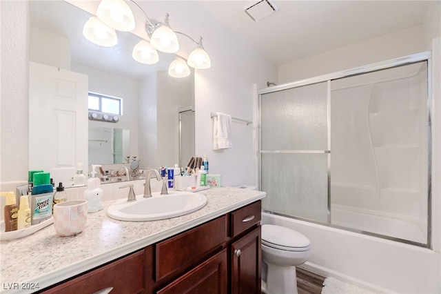 full bathroom featuring vanity, hardwood / wood-style floors, toilet, and combined bath / shower with glass door