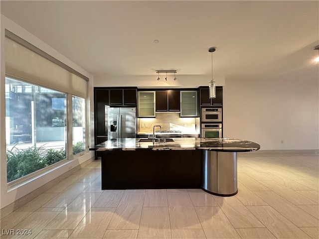 kitchen featuring pendant lighting, appliances with stainless steel finishes, sink, and an island with sink