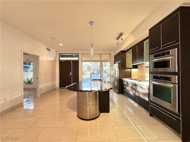 kitchen featuring a kitchen island with sink, stainless steel appliances, plenty of natural light, and hanging light fixtures