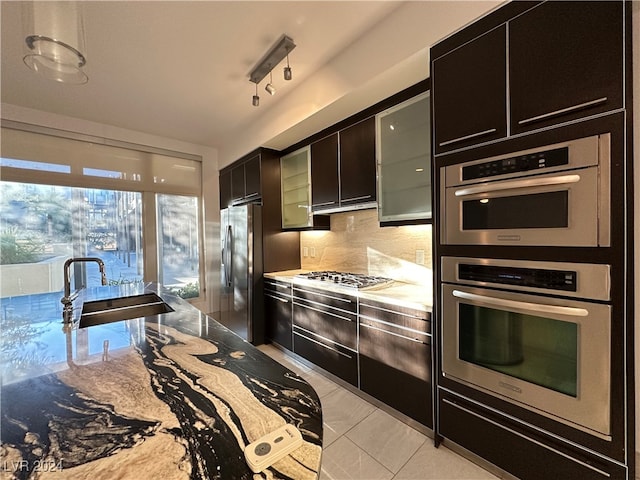 kitchen featuring tasteful backsplash, light tile patterned flooring, appliances with stainless steel finishes, sink, and rail lighting