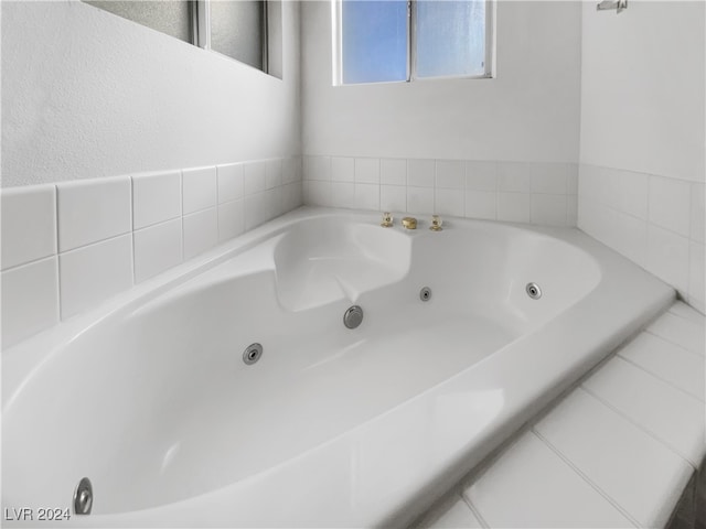 bathroom with tiled tub and tile patterned floors