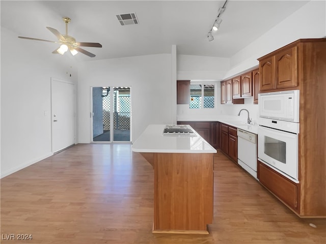 kitchen with a center island, white appliances, rail lighting, and light hardwood / wood-style flooring