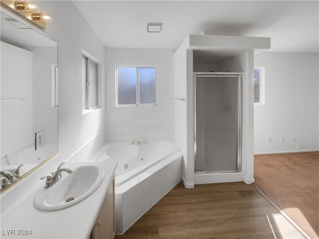 bathroom with hardwood / wood-style flooring, vanity, and plus walk in shower