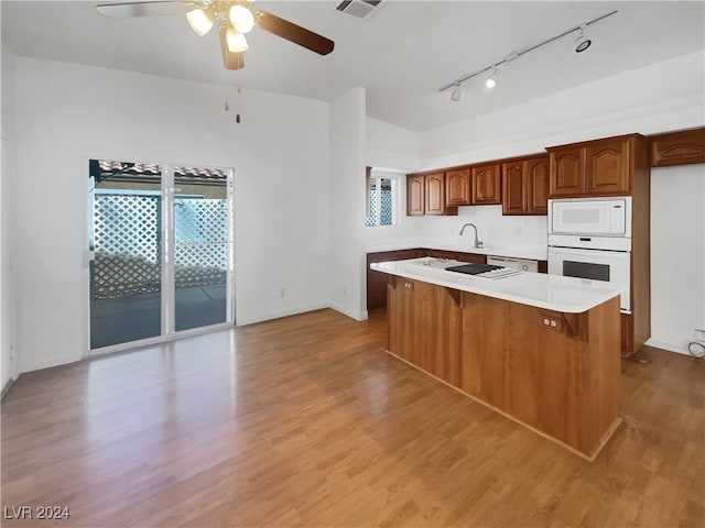 kitchen with a center island, white appliances, a breakfast bar area, and light hardwood / wood-style flooring