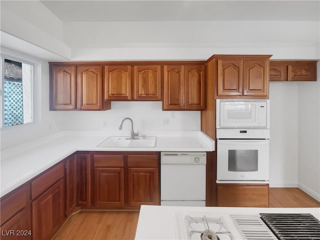 kitchen featuring light wood-type flooring, white appliances, and sink