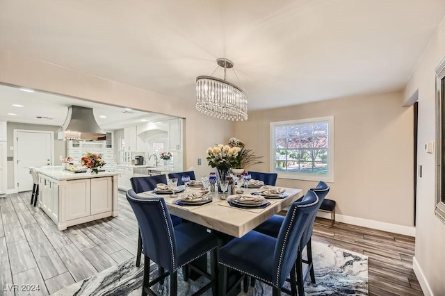 dining room with light hardwood / wood-style floors, an inviting chandelier, and sink