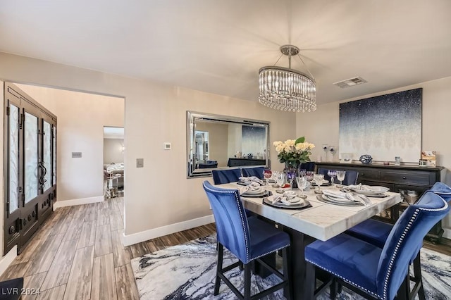 dining area with french doors, a notable chandelier, and hardwood / wood-style floors