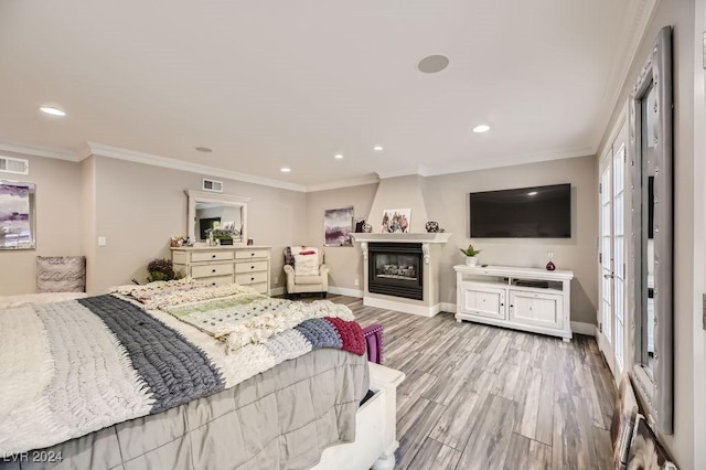 bedroom with a fireplace, light wood-type flooring, and crown molding