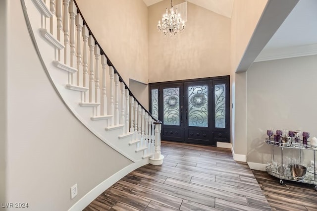 foyer featuring a chandelier, a high ceiling, french doors, crown molding, and wood-type flooring