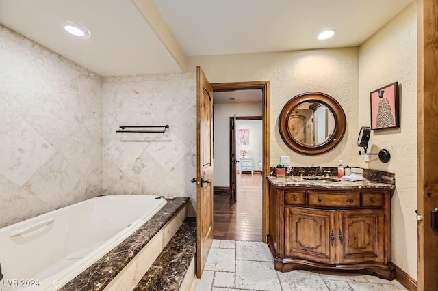 bathroom with a relaxing tiled tub and vanity