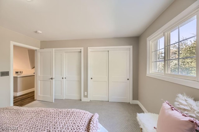 bedroom featuring multiple closets and light carpet