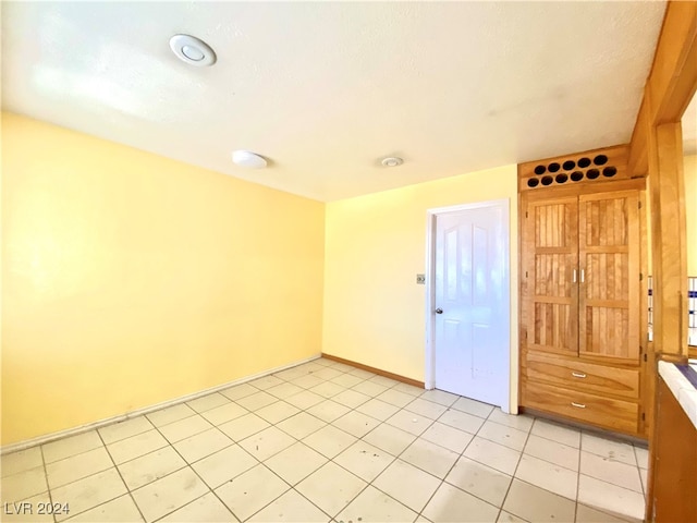 tiled empty room featuring a textured ceiling