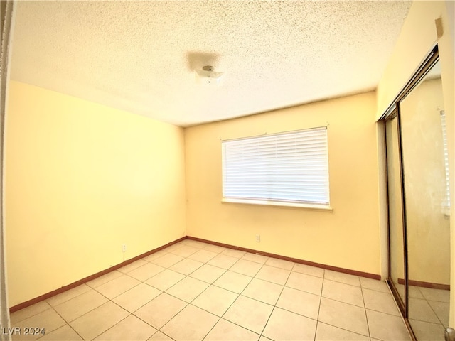 unfurnished bedroom with a closet, a textured ceiling, and light tile patterned floors