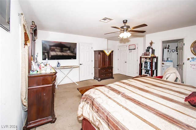 bedroom featuring light colored carpet, ceiling fan, and ensuite bath