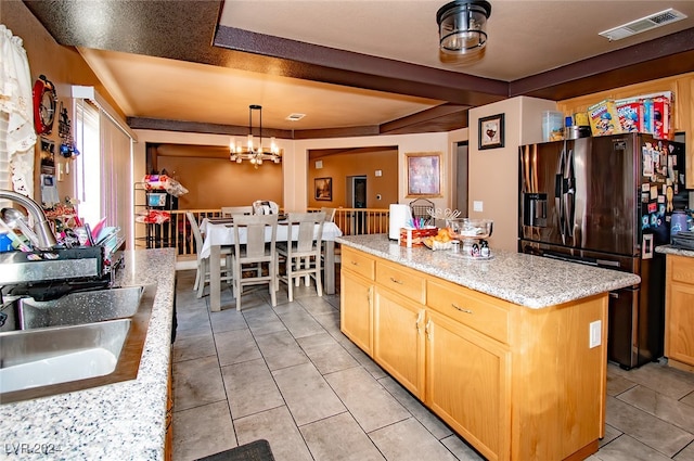 kitchen with fridge with ice dispenser, decorative light fixtures, a kitchen island, and light stone countertops