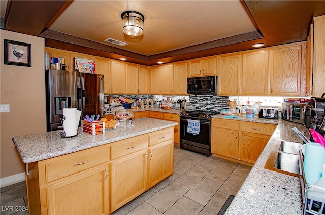 kitchen with black appliances, light stone counters, tasteful backsplash, light tile patterned floors, and a raised ceiling