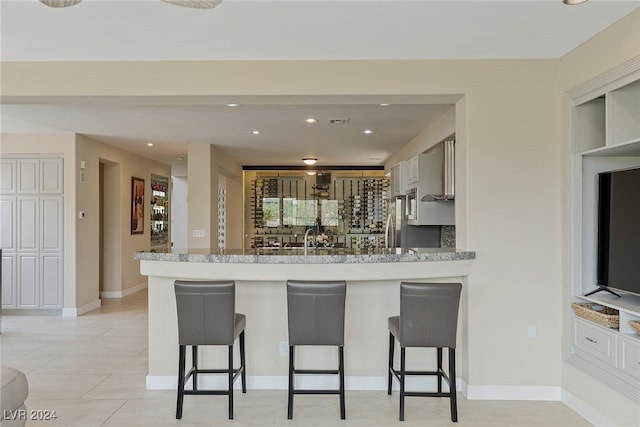 kitchen featuring gray cabinets, a breakfast bar area, light tile patterned floors, and kitchen peninsula