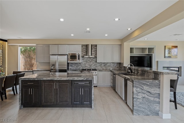 kitchen with wall chimney exhaust hood, sink, tasteful backsplash, gray cabinetry, and appliances with stainless steel finishes