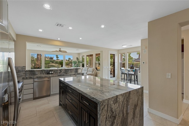 kitchen with dark brown cabinetry, a wealth of natural light, dark stone countertops, and appliances with stainless steel finishes